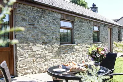 a table in front of a stone cottage at Yr Onnen Aberaeron in Llanarth