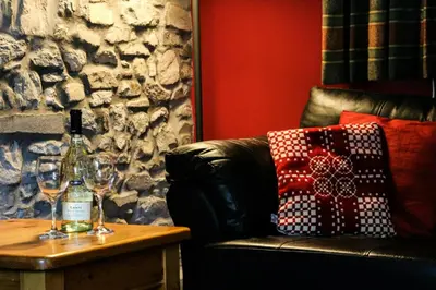 a living room with a couch and a table with wine glasses at Yr Onnen Aberaeron in Llanarth