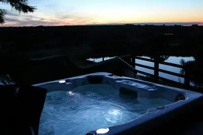 a jacuzzi tub with the sunset in the background at Yr Onnen Aberaeron in Llanarth