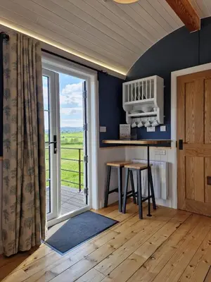 a kitchen with a table and a large window at Oak Moor Shepherd Hut - Brecon Beacons, LD3 7TD in Tal-y-llyn