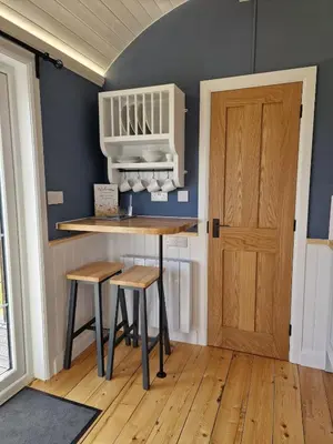 a kitchen with a table and stools and a door at Oak Moor Shepherd Hut - Brecon Beacons, LD3 7TD in Tal-y-llyn