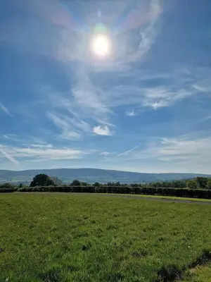 a field of grass with the sun in the sky at Oak Moor Shepherd Hut - Brecon Beacons, LD3 7TD in Tal-y-llyn