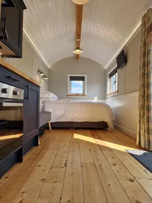 a bedroom with a bed and wooden floors at Long Meadow Shepherd Hut - Brecon Beacons, LD3 7TD in Tal-y-llyn