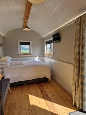 a bedroom with a bed and a tv in a room at Long Meadow Shepherd Hut - Brecon Beacons, LD3 7TD in Tal-y-llyn
