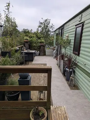 a patio with a table next to a green trailer at Aberystwyth holiday village walking distance to beach, town great outside space parking next to property in Aberystwyth