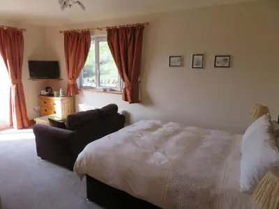 a bedroom with a bed and a couch and a window at Heulwen Guest House in Dolgellau