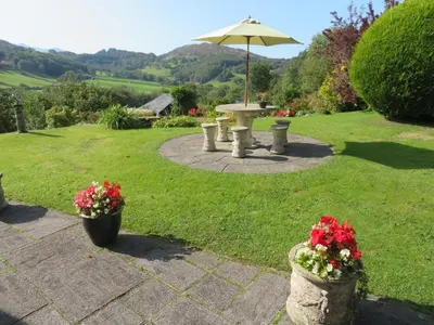 a picnic table with an umbrella in a garden at Heulwen Guest House in Dolgellau