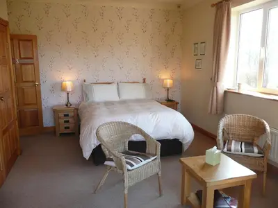 a bedroom with a bed and two chairs and a table at Heulwen Guest House in Dolgellau