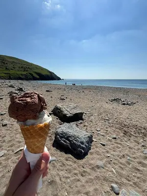 a person holding an ice cream cone on a beach at Welsh Bayview Retreat 2-Bed Caravan & 2-Bed Chalet at Clarach Bay Holiday Village in Aberystwyth