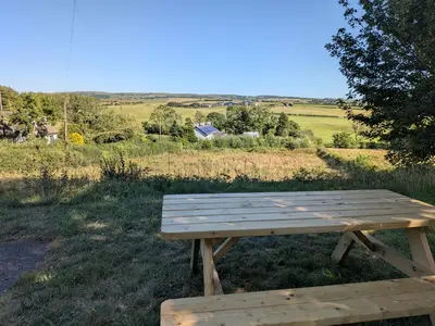 a wooden picnic table sitting in the middle of a field at Aelybryn in Llangwyryfon