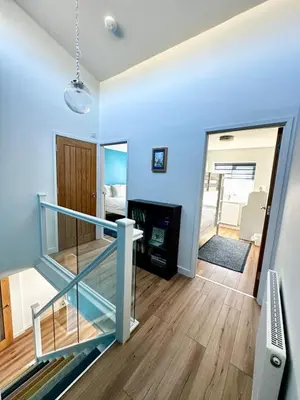 a staircase in a living room with blue walls at Ynyslas View in Aberdyfi