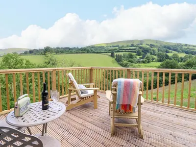 a deck with two chairs and a table with a bottle of wine at The Owlet in Llanidloes