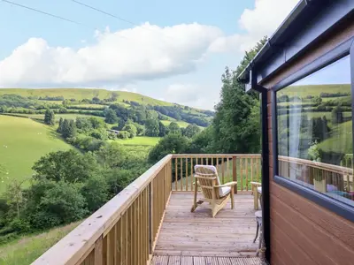 a deck with a chair and a view of the hills at The Owlet in Llanidloes