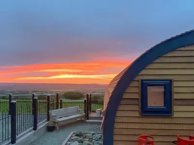 a building with a bench and a sunset in the background at Sunset Holiday Pod - Uk48592 in Church Stretton