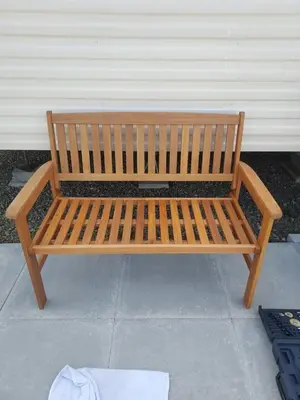 a wooden bench is sitting on a sidewalk at 63 Bardsey View Holiday Park in Mydroilin