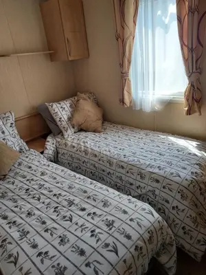 two beds in a small room with a window at 63 Bardsey View Holiday Park in Mydroilin