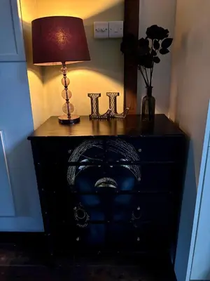 a black dresser with a lamp on top of it at The Little Laura Ashley House in Machynlleth
