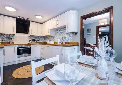 a kitchen with white cabinets and a table and chairs at Peaceful Barn Near Cader Idris in Dolgellau
