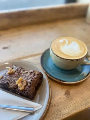 a cup of coffee and a piece of cake on a table at Brewe's Loft in Farden