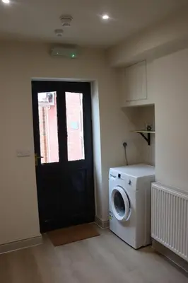 a laundry room with a black door and a washing machine at Brewe's Loft in Farden