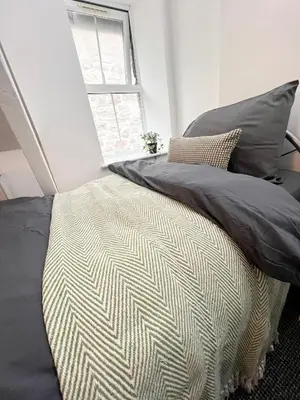 a bedroom with a bed with gray pillows and a window at Cosy Cader Cottage in Dolgellau