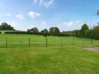 a fence in a field with a horse in the distance at Brown Hare - Uk49799 in Brecon