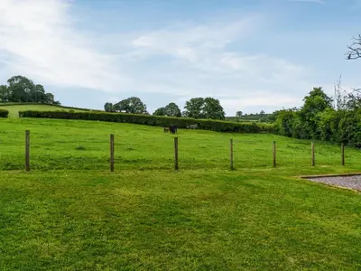 a fence in a field with a horse in the distance at Sweet Briar - Uk49797 in Brecon