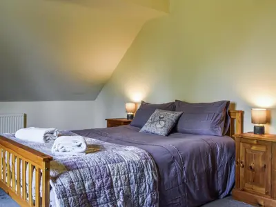 a bedroom with a bed with purple sheets and two night stands at Priory Cottage in Clifford