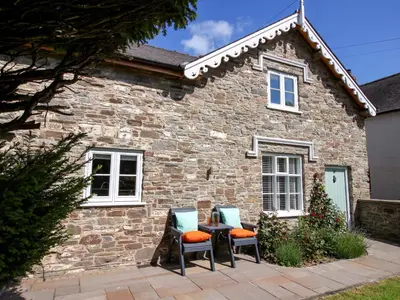 two chairs and a table in front of a stone house at 10 Bridge Street in Craven Arms