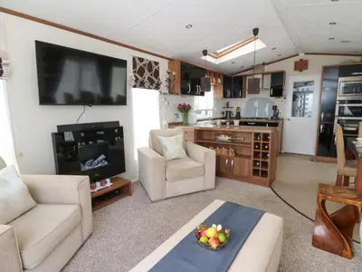 a living room with a couch and a kitchen at Ty Seren in New Quay