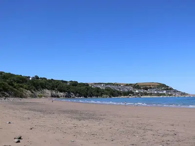 a beach with people walking on the sand and the ocean at Ty Seren in New Quay