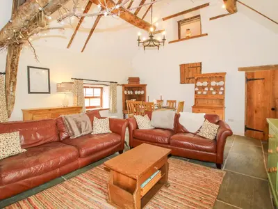 a living room with brown leather couches and a table at The Long House in Oswestry