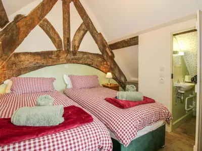 a bedroom with two beds with red and white sheets at The Long House in Oswestry