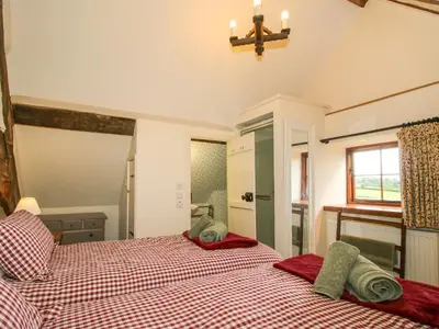 a bedroom with two beds and a window at The Long House in Oswestry