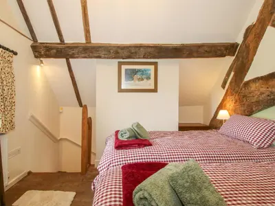 a bedroom with a bed with red and green sheets at The Long House in Oswestry