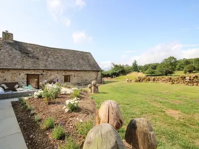 a stone house with wooden logs in a yard at The Long House in Oswestry
