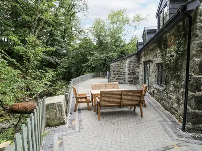 a patio with two benches and a table at Frongoch Old Power House in Dolgellau