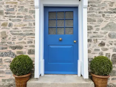 a blue door on a stone house with two plants at Upper Dolarddyn in Welshpool