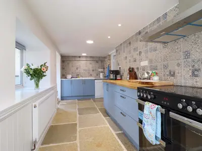 a large kitchen with blue cabinets and tile walls at Upper Dolarddyn in Welshpool