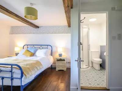 a bedroom with a blue bed and a bathroom at Upper Dolarddyn in Welshpool
