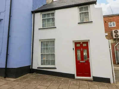 a white house with a red door on a street at Hafan Fach in Aberystwyth