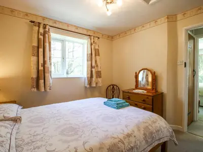 a bedroom with a bed and a mirror and a window at Caradoc Cottage in Church Stretton