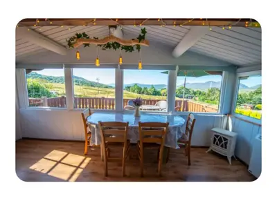 a dining room with a table and chairs on a porch at Snowdonia Escapes# Scenic Log Cabin with Views, WIFI & 2 Double bedrooms in Trawsfynydd