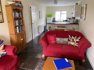 a living room with a red couch and a table at Riverside Bungalow in Llanbedr