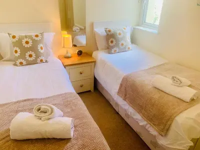 two beds in a room with towels on them at Riverside Bungalow in Llanbedr