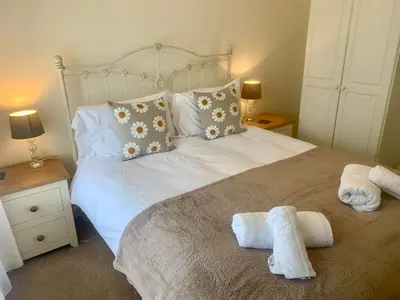 a bedroom with a white bed with towels on it at Riverside Bungalow in Llanbedr