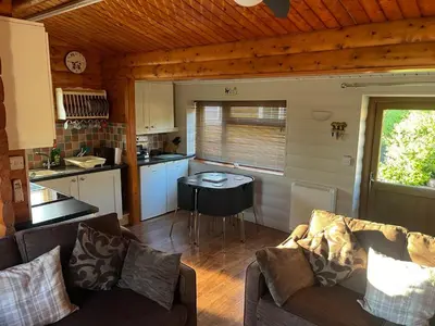 a living room with a couch and a table in a kitchen at Home From Home LogCabin in Trawsfynydd