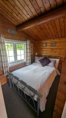 a bedroom with a bed in a log cabin at Happy Place LogCabin in Trawsfynydd