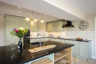 a kitchen with a black counter top and a sink at Hen Llwyn by Birch Stays New Home in Llangadwaladr