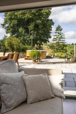 a living room with a couch and a large window at Hen Llwyn by Birch Stays New Home in Llangadwaladr
